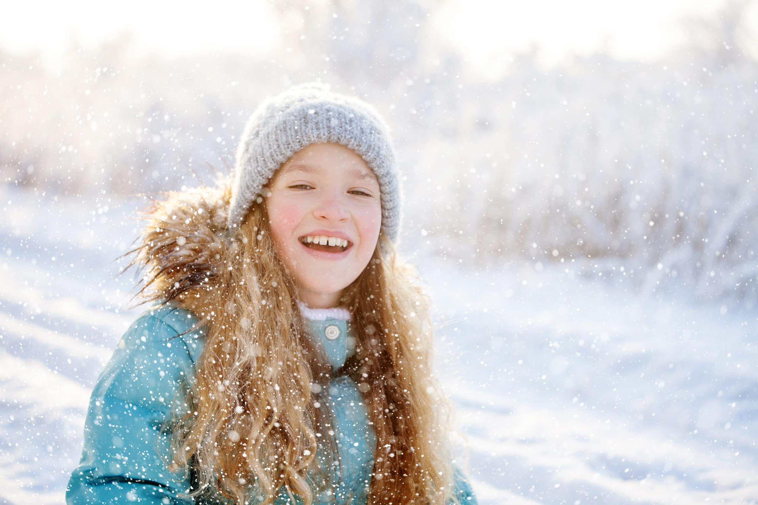young girl smilling in winter clothes in the snow