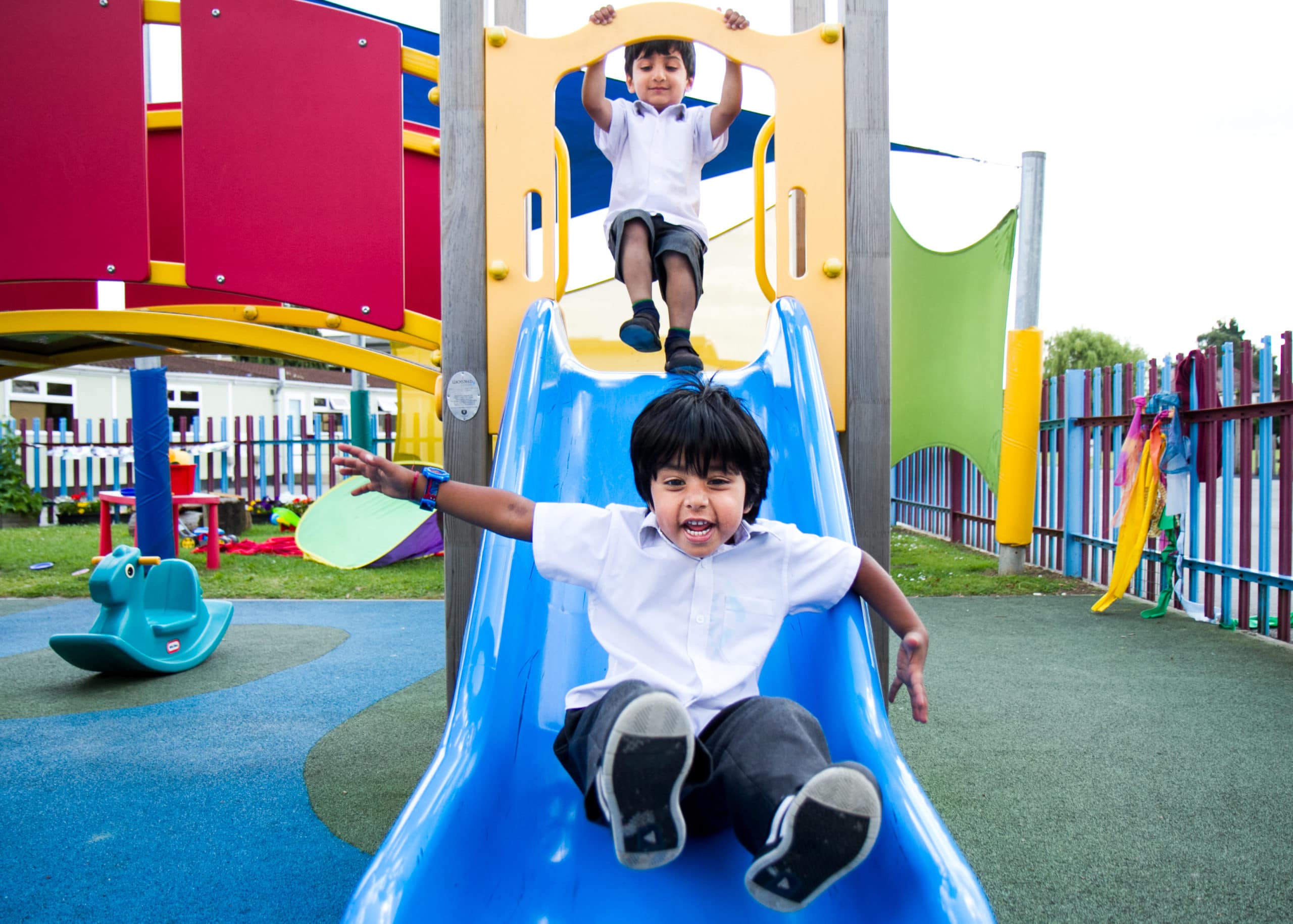 children going down slide in small park