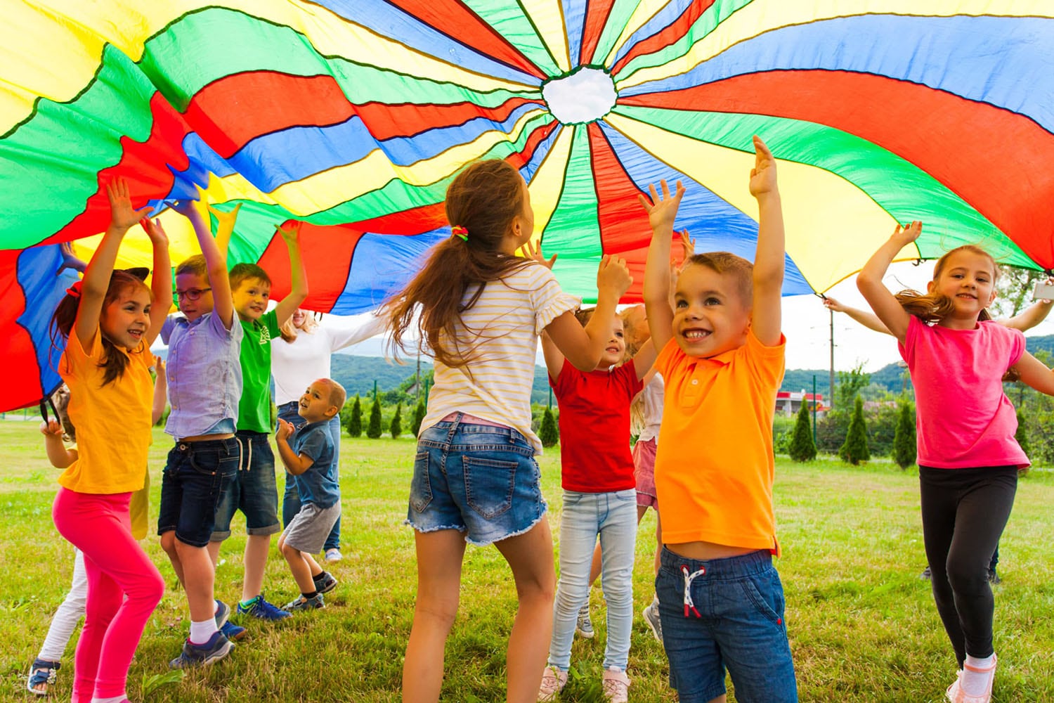 children playing in park under large umbrella