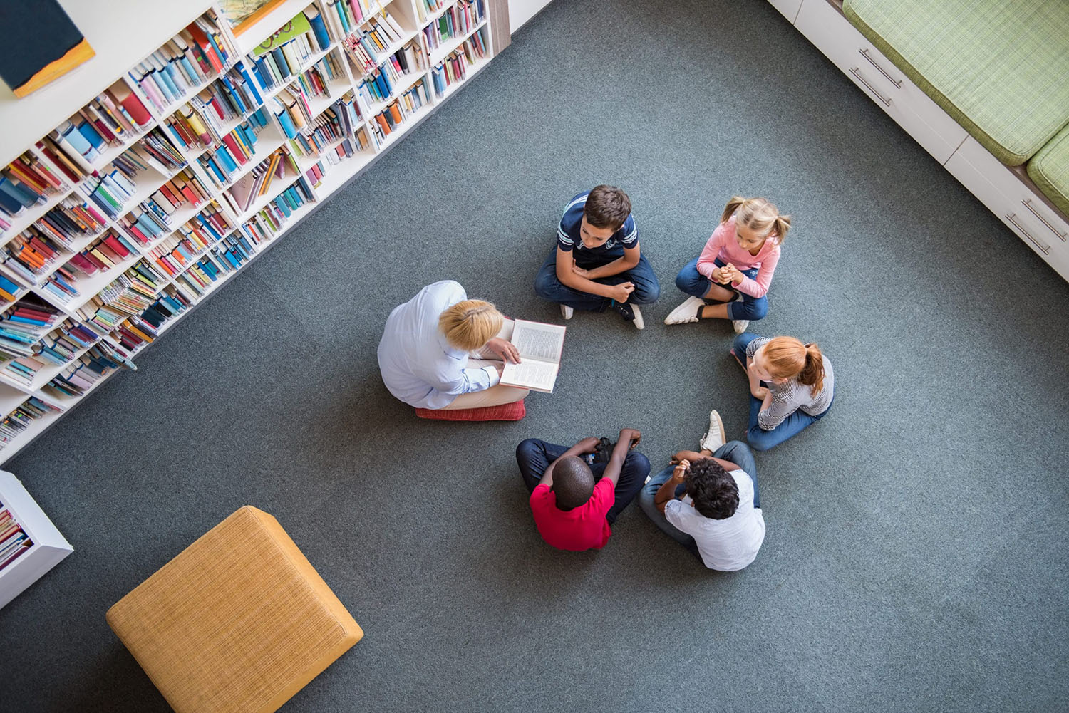 children sat in circle with teacher reading