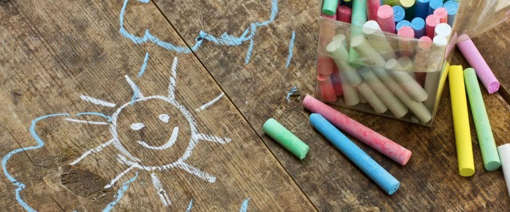 Coloured chalk next to a drawing of the sun