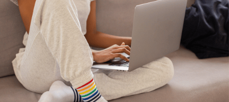 A person sitting on a sofa whilst using their laptop