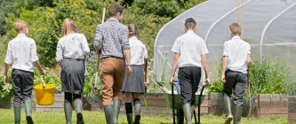 5 school children and a teacher gardening