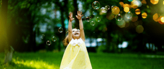 A girl jumping in the air trying to catch bubbles