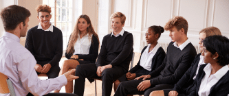 7 school children sitting opposite a teacher