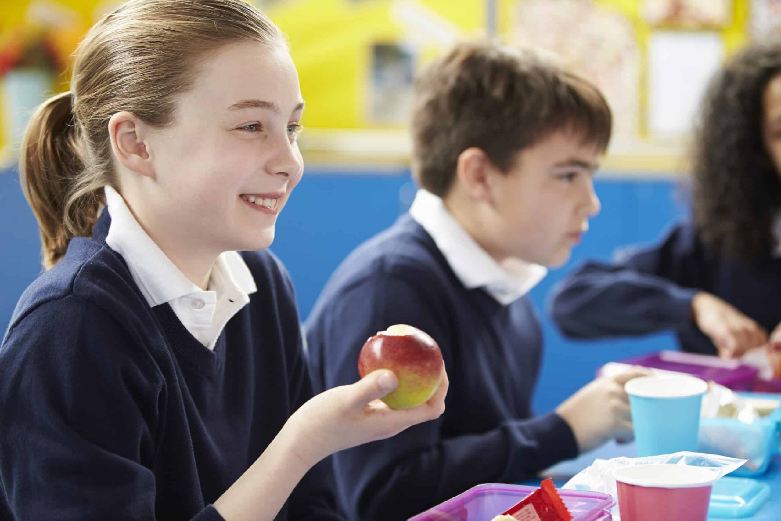 School girl eating apple in a nurture group snack time