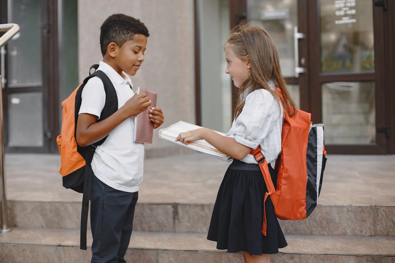 pexels-gustavo-fring-5621885 Two school children are stood chatting to each other.