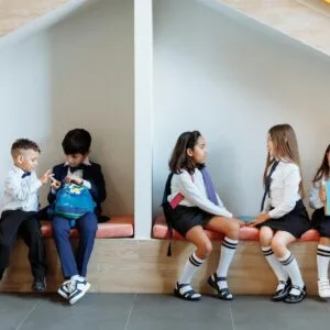 School kids sit on a bench chatting to each other calmly.