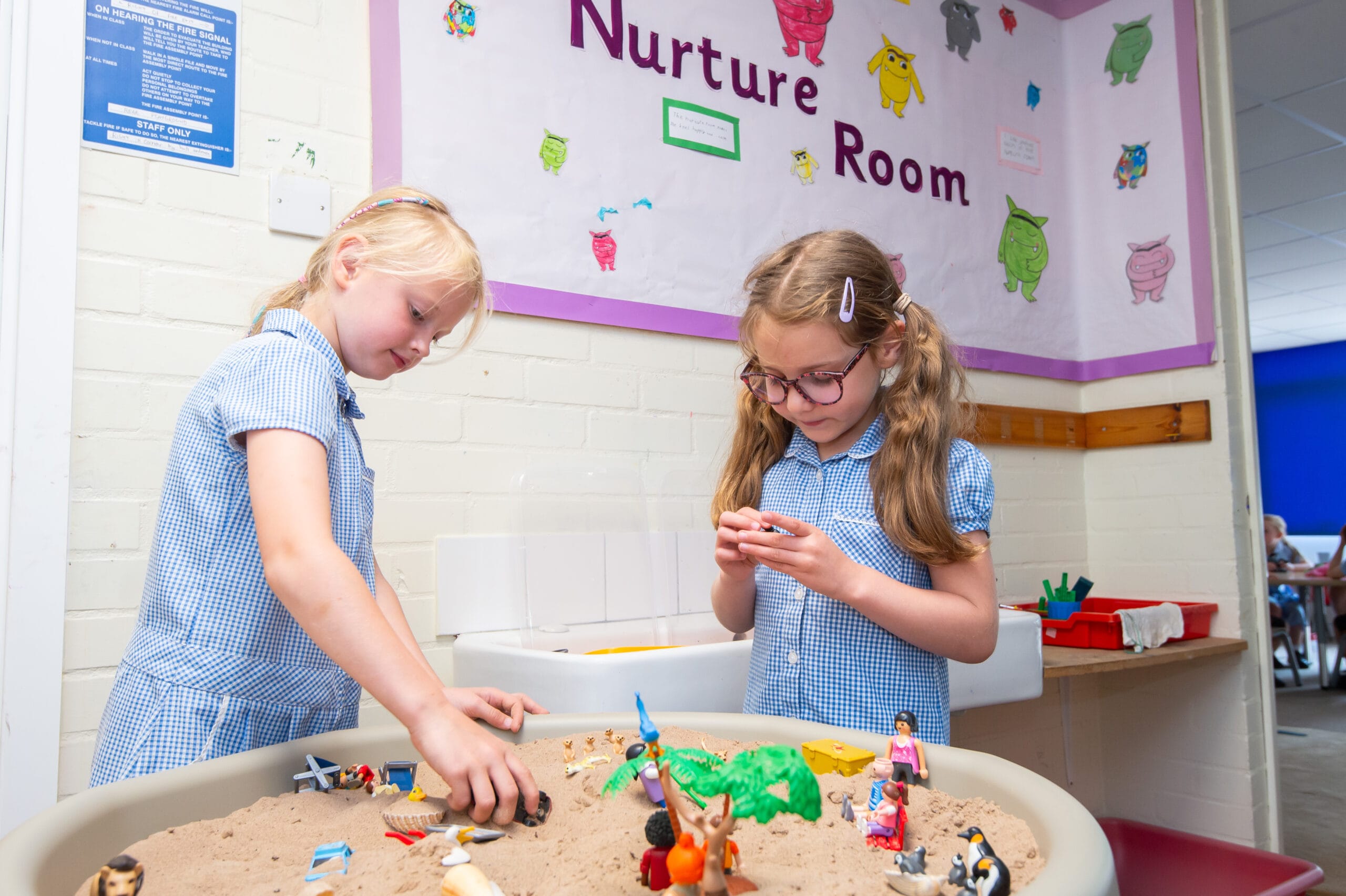 Two school children engage in sand play in a nurture room.