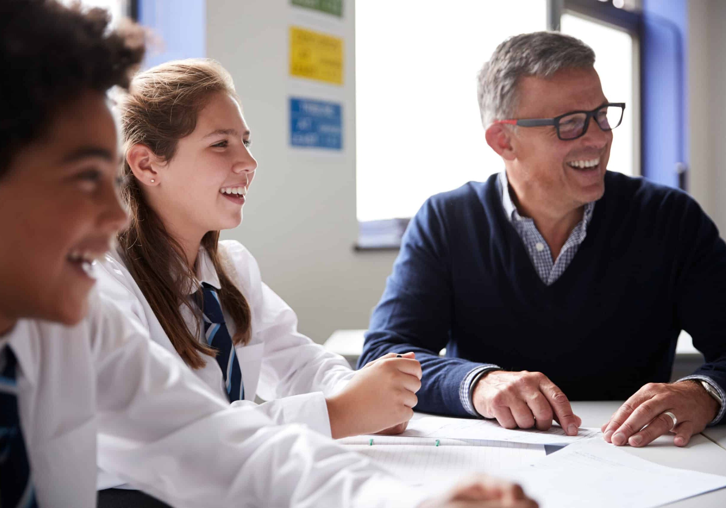 A teacher and two students sitting next to eachother and smiling