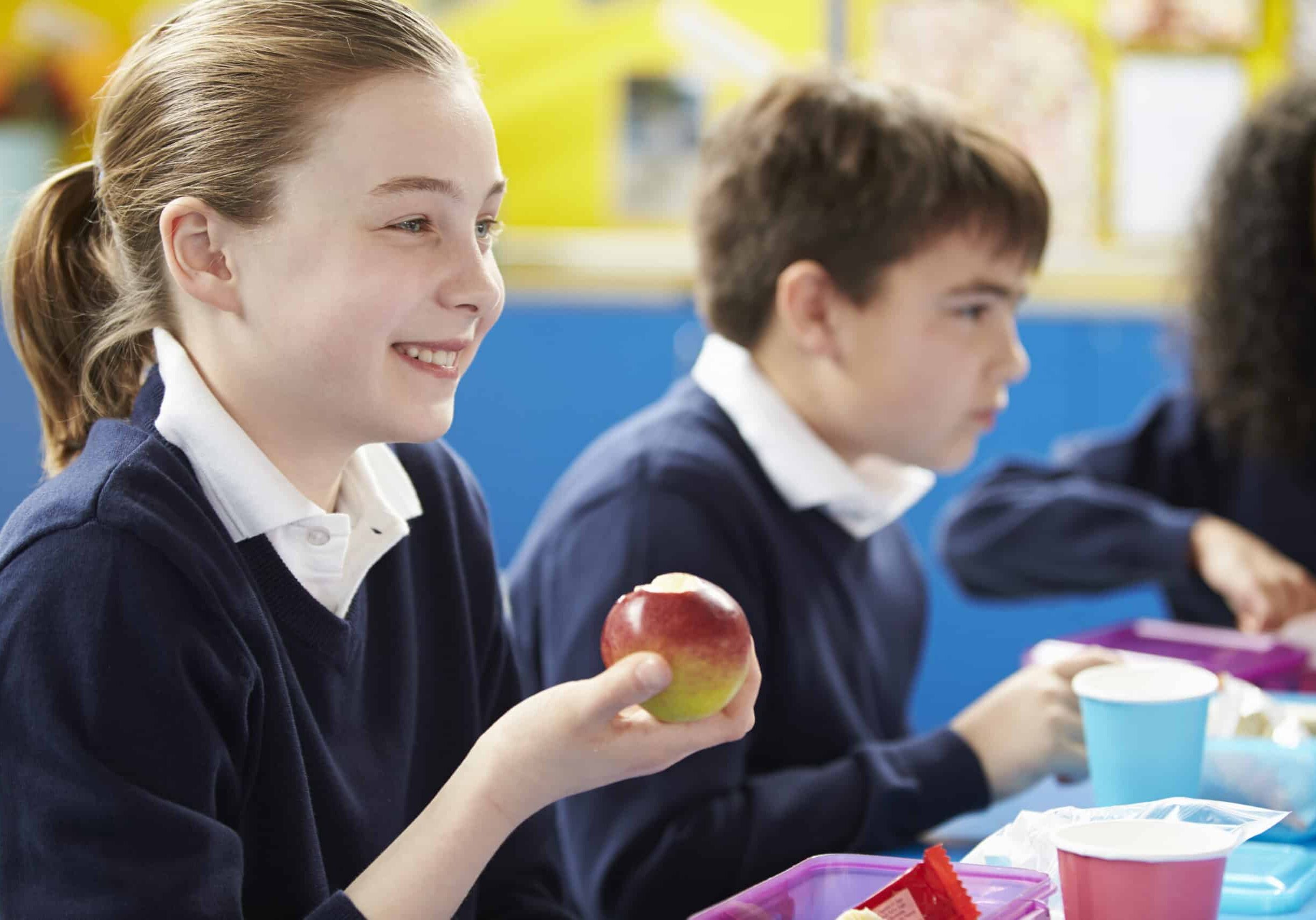 School girl eating apple in a nurture group snack time